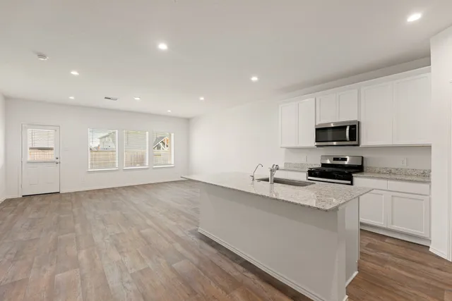 a kitchen with granite countertop a sink cabinets and stainless steel appliances