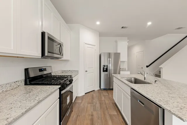a kitchen with stainless steel appliances granite countertop a sink stove and refrigerator