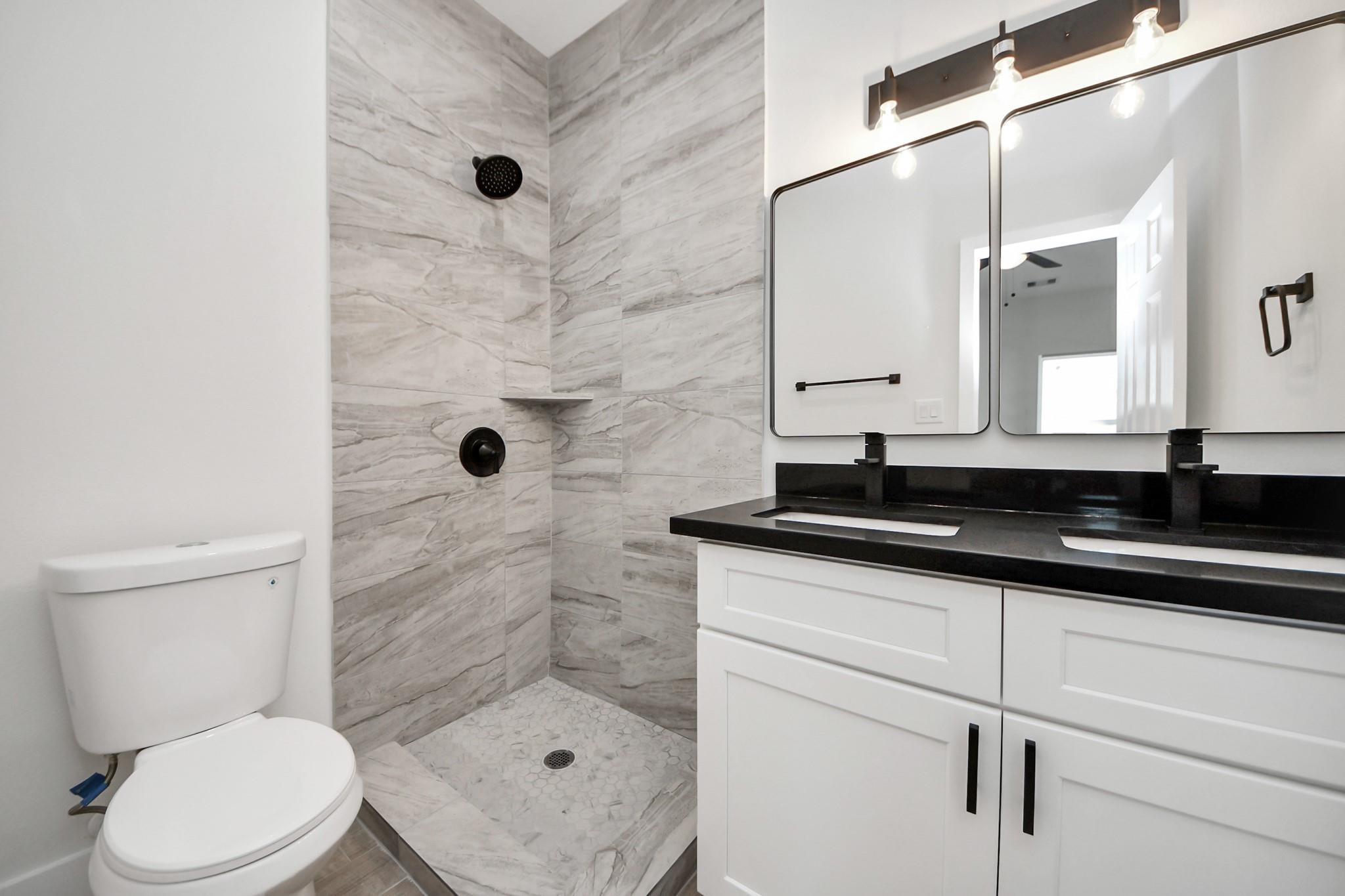 8015 Elbert Street, Unit A/B Houston, TX 77028 - Photo 9 of 12 a bathroom with a granite countertop sink a toilet a mirror and shower