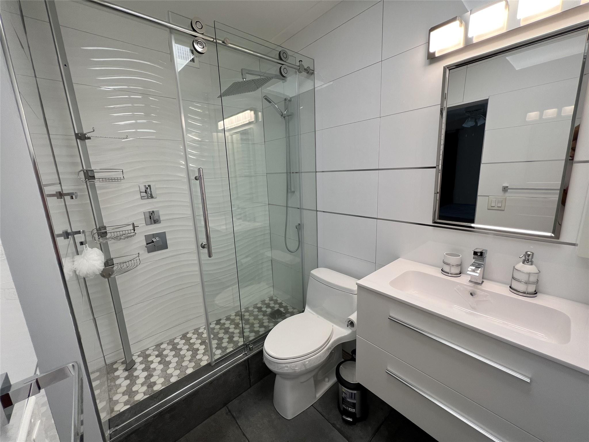 999 North Riverside Drive, Unit 9 Pompano Beach, FL 33062 - Photo 8 of 11 a bathroom with a sink a toilet a mirror and shower