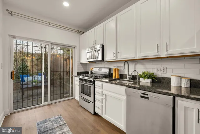 a kitchen with stainless steel appliances granite countertop a stove a sink and white cabinets