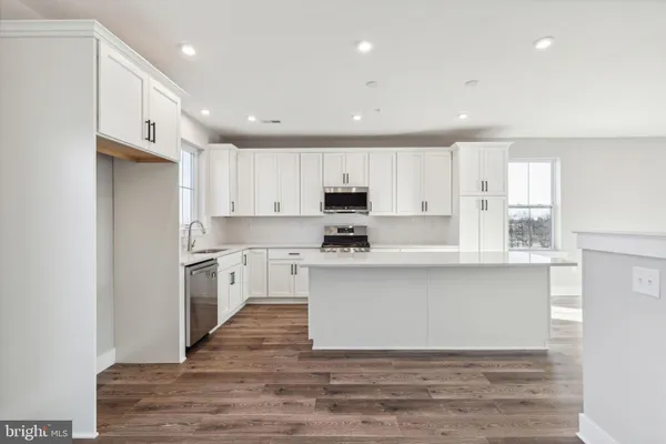 a kitchen with stainless steel appliances granite countertop a stove a sink and white cabinets