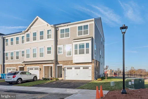 a front view of a building with a yard and parking space