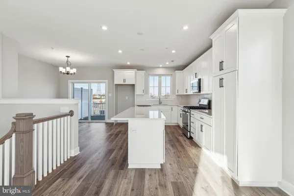 a large white kitchen with lots of counter space wooden floor and stainless steel appliances