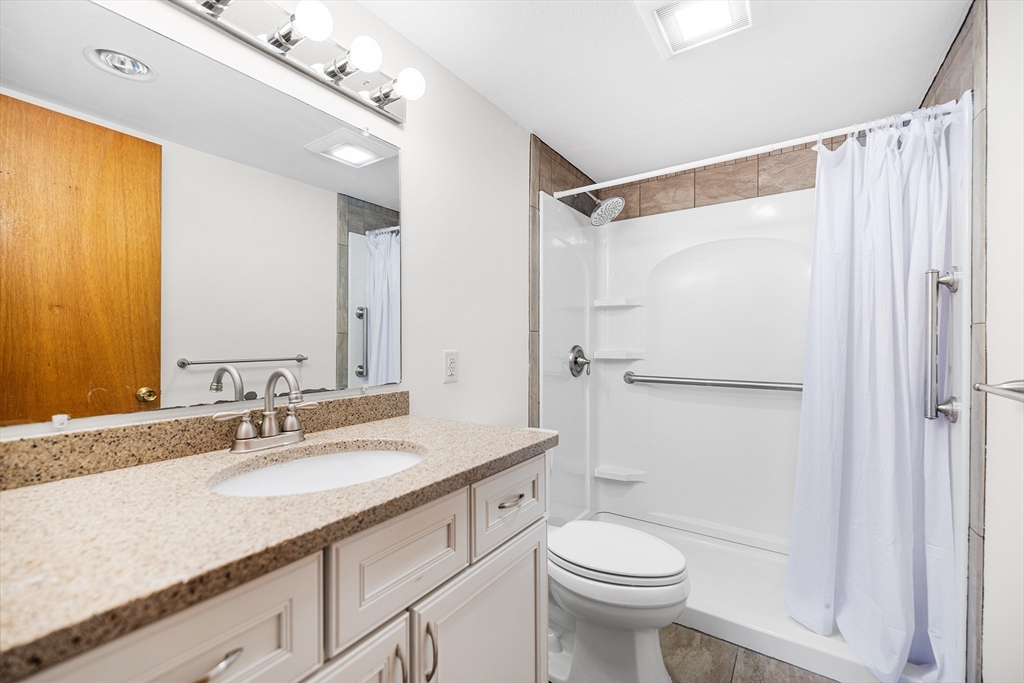 40 Main Street, Unit 505 Stoneham, MA 02180 - Photo 15 of 27 a bathroom with a granite countertop sink toilet and shower