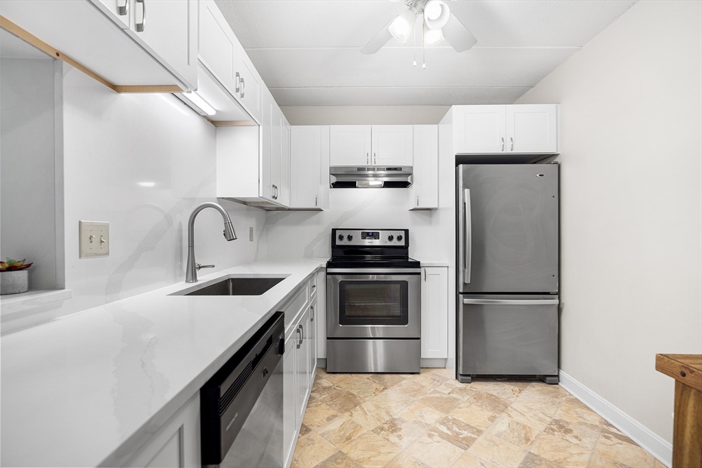 40 Main Street, Unit 505 Stoneham, MA 02180 - Photo 2 of 27 a kitchen with refrigerator a sink and white cabinets