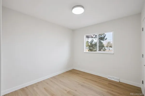 an empty room with wooden floor and window