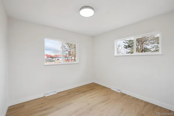 an empty room with wooden floor and window
