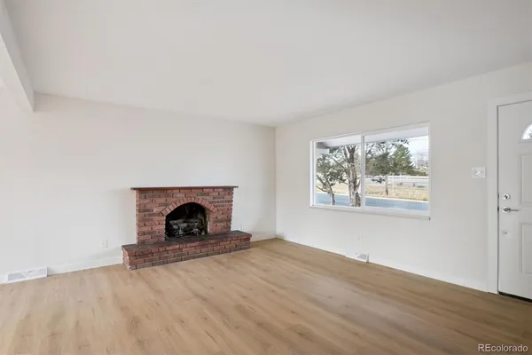 an empty room with windows and fireplace