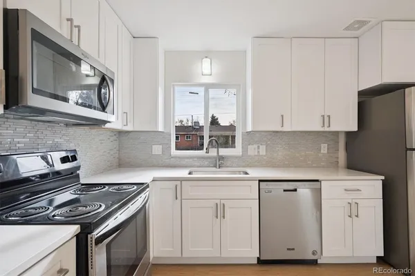 a kitchen with white cabinets and appliances