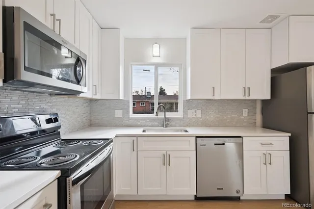 a kitchen with white cabinets and appliances