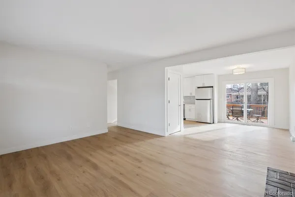 a view of an empty room with a window and wooden floor