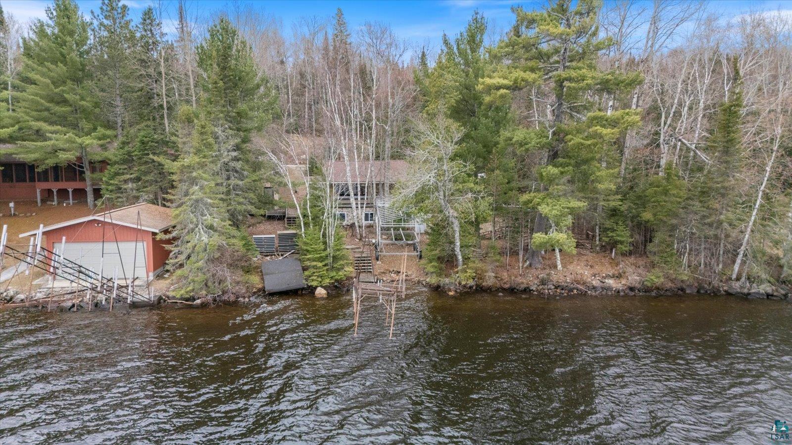 2014 West Frazer Bay Road Cook, MN 55723 - Photo 11 of 26 Waterfront property featuring a main residence, a detached boathouse with an overhead door, and multiple dock structures extending into the water