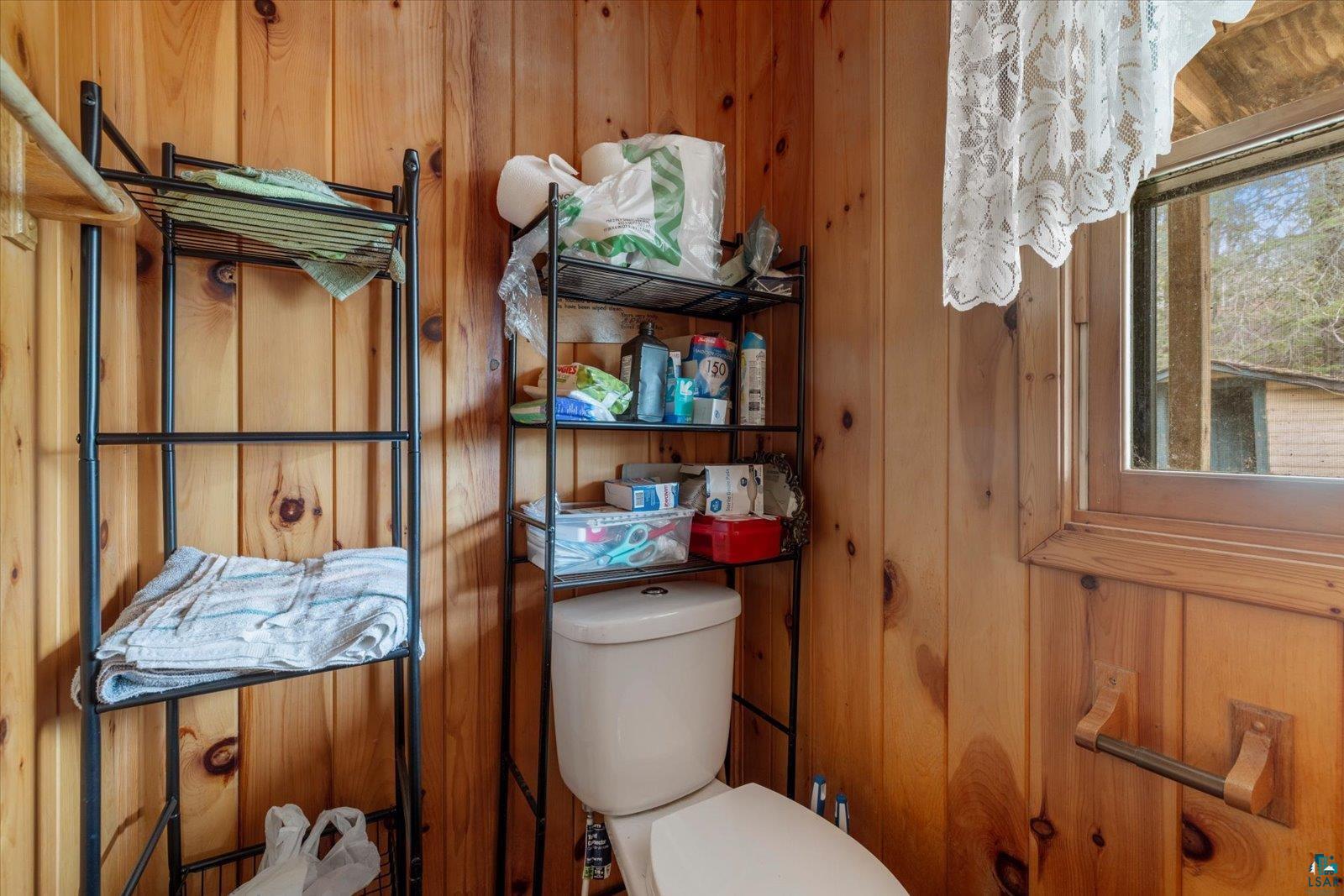 2014 West Frazer Bay Road Cook, MN 55723 - Photo 15 of 26 Wood-paneled room featuring a window with natural light, a toilet, and built-in shelving