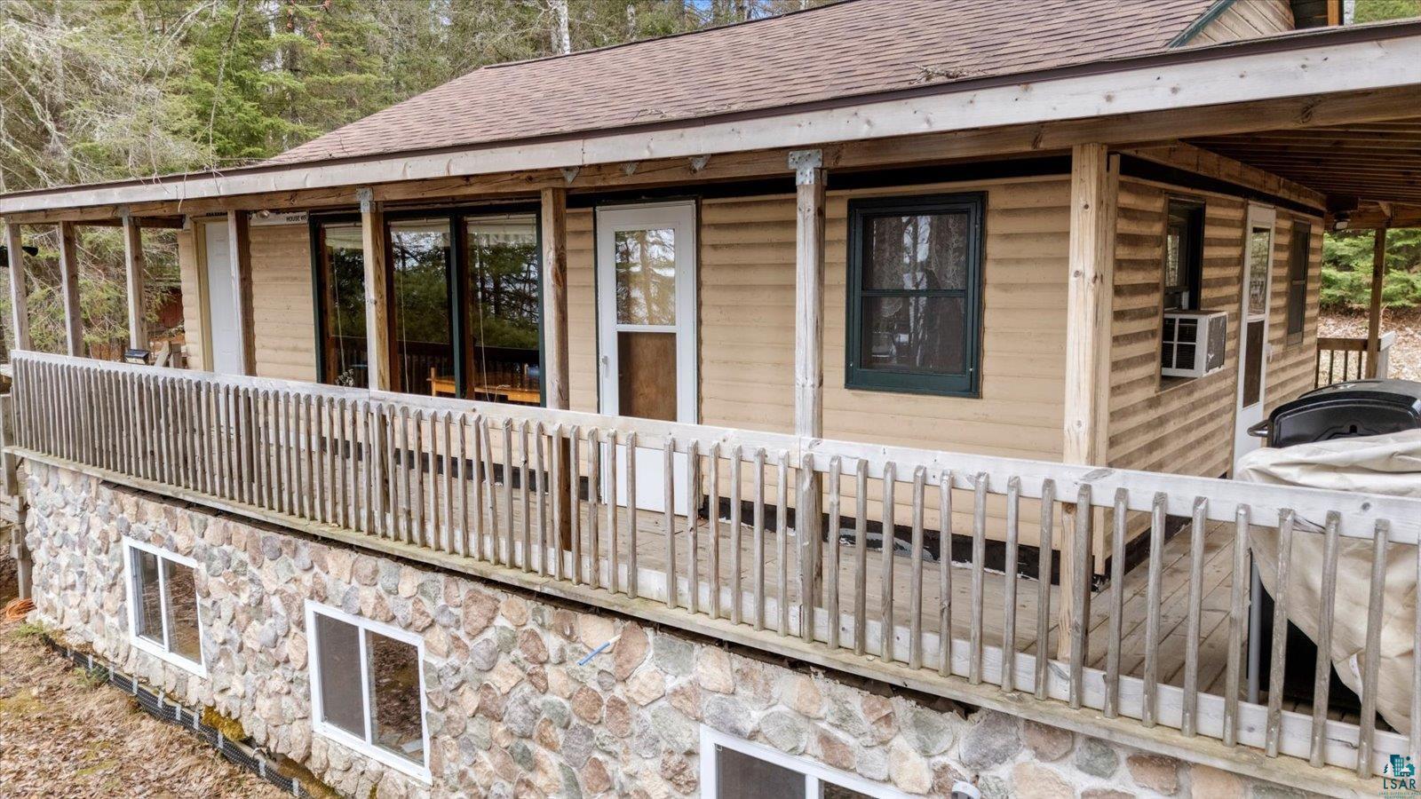 2014 West Frazer Bay Road Cook, MN 55723 - Photo 16 of 26 Exterior featuring a stone foundation, wood siding, and a covered porch with a wooden railing