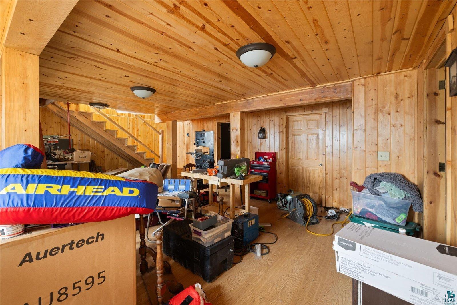 2014 West Frazer Bay Road Cook, MN 55723 - Photo 18 of 26 Wood-paneled room featuring a staircase with wood railings, a paneled door, and two flush-mount ceiling lights