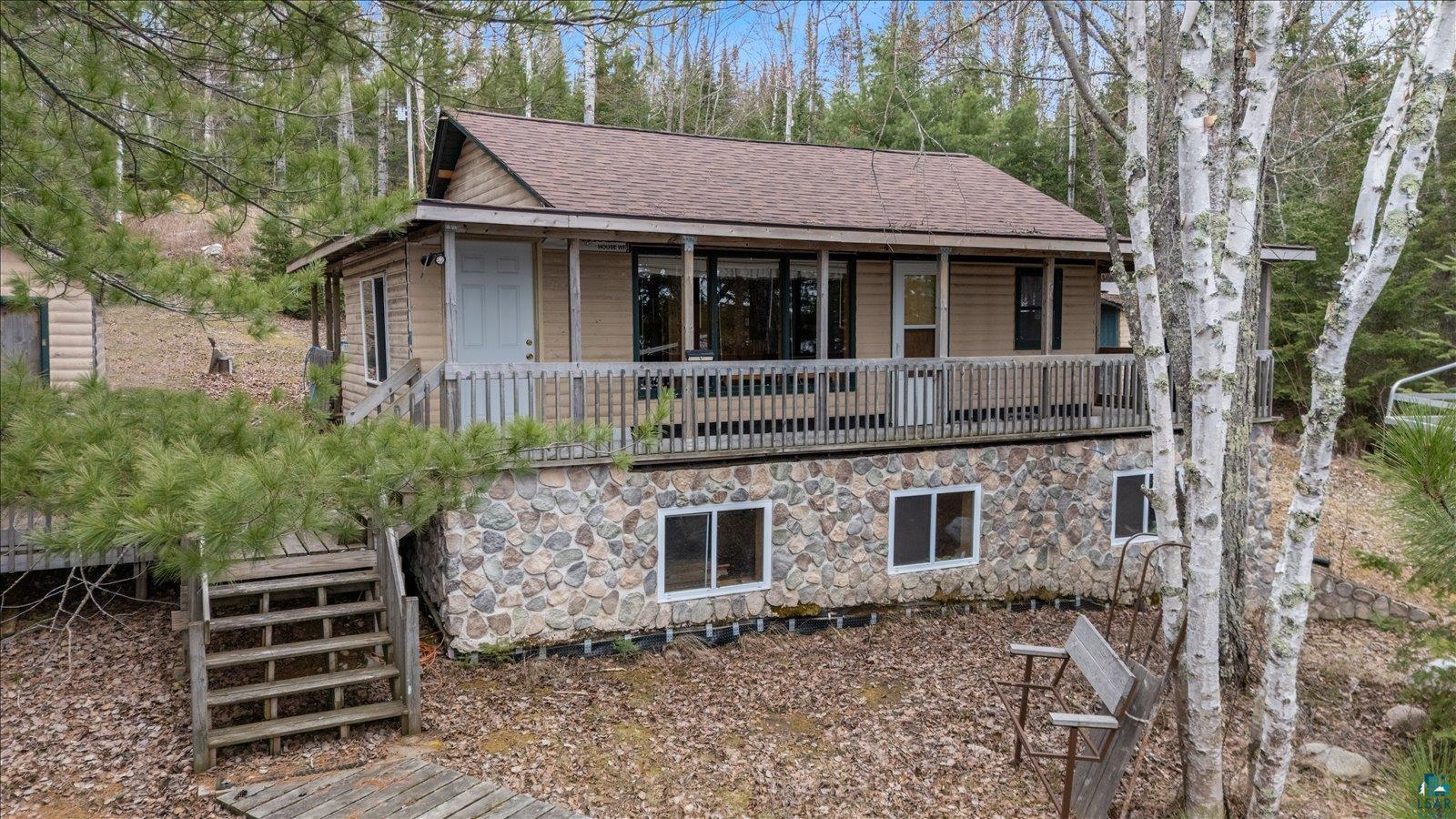 2014 West Frazer Bay Road Cook, MN 55723 - Photo 22 of 26 Exterior featuring a stone-faced lower level, wood siding, and a spacious elevated deck with railing