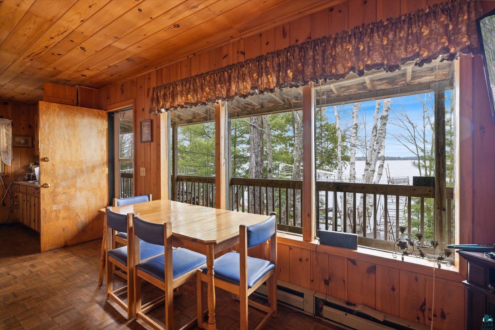 2014 West Frazer Bay Road Cook, MN 55723 - Photo 5 of 26 Dining area featuring wood-paneled walls and ceiling, wood-finish flooring, and expansive windows showcasing a balcony and water scenery