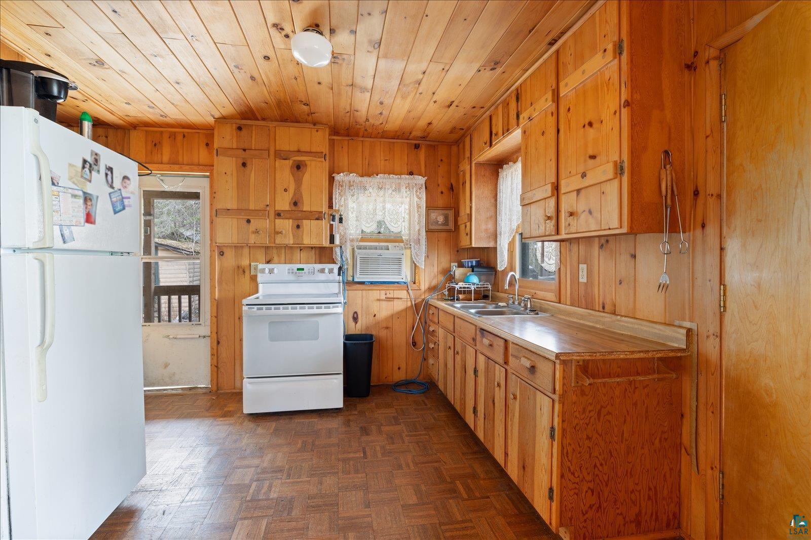 2014 West Frazer Bay Road Cook, MN 55723 - Photo 7 of 26 Kitchen featuring knotty pine paneling, wood-finish flooring, wood cabinetry with exposed hinges, and a double basin stainless steel sink
