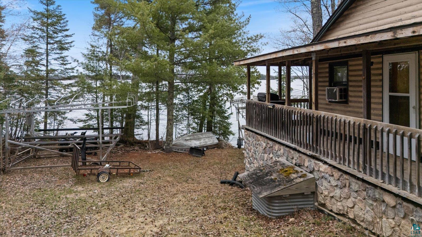 2014 West Frazer Bay Road Cook, MN 55723 - Photo 10 of 26 Log cabin exterior featuring a covered porch with wood railings, a stone foundation, and a window air conditioning unit