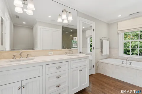a bathroom with a double vanity sink mirror and a bathtub