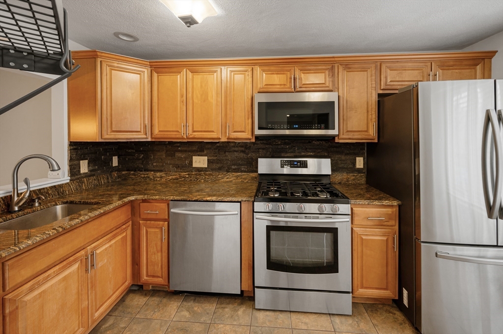 4 Deer Path, Unit 3 Maynard, MA 01754 - Photo 3 of 27 a kitchen with granite countertop a sink stove and refrigerator