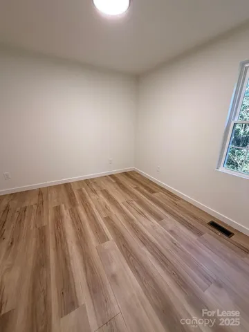 a view of a room with wooden floor and a window