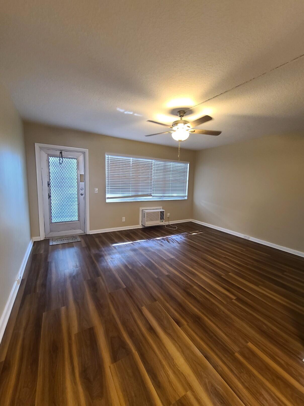 82 Canterbury D, Unit 82 West Palm Beach, FL 33417 - Photo 3 of 13 wooden floor in an empty room with a window