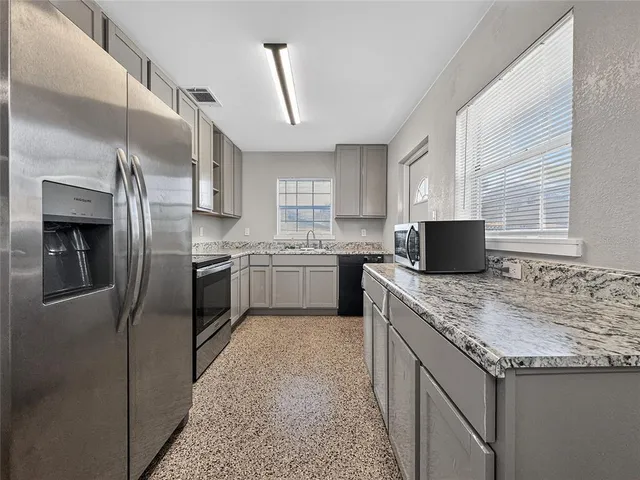 a kitchen with granite countertop a sink stove and refrigerator