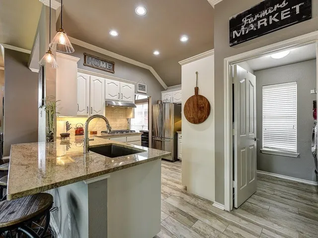 a kitchen with stainless steel appliances granite countertop a sink a stove and a refrigerator