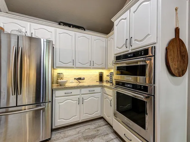 a kitchen with cabinets stainless steel appliances and a window