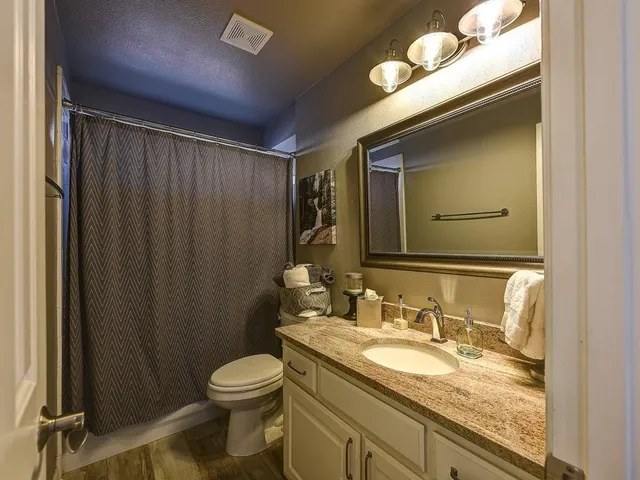 a bathroom with a granite countertop sink toilet and mirror
