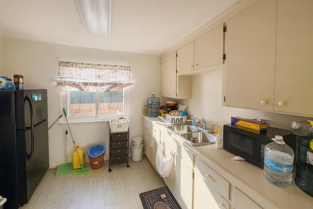 a kitchen with a refrigerator and white cabinets