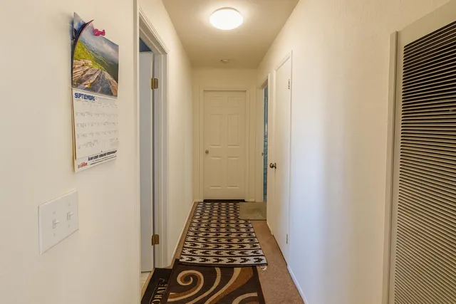 a view of a hallway with wooden floor and a bathroom