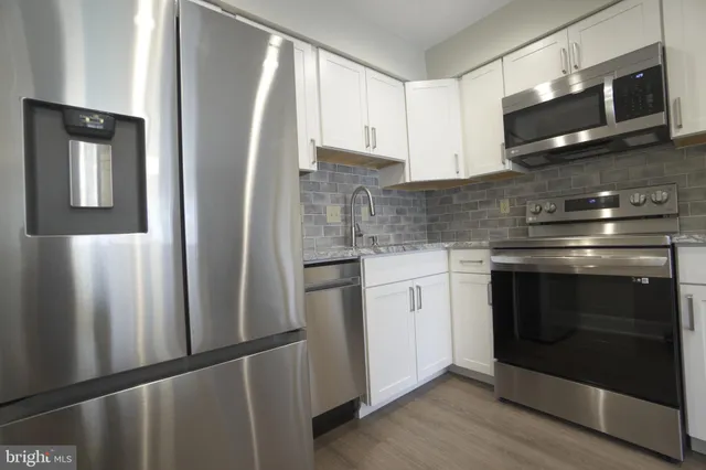 a kitchen with stainless steel appliances white cabinets and a refrigerator