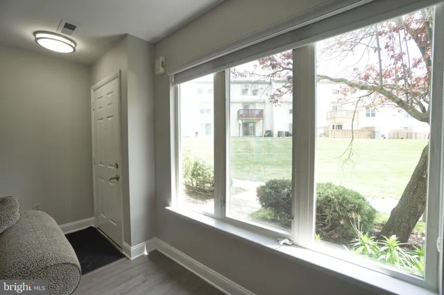 a view of an empty room with wooden floor and windows