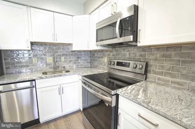 a kitchen with granite countertop white cabinets stainless steel appliances and a sink