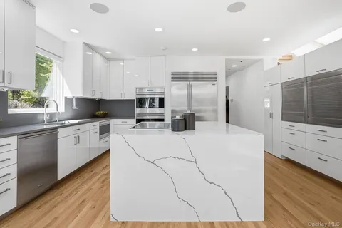 a large white kitchen with cabinets a sink a window and stainless steel appliances