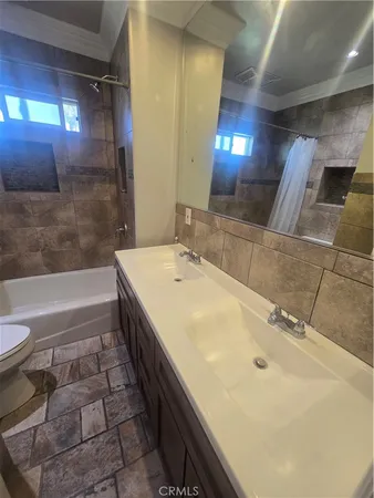 a bathroom with a double vanity sink a toilet and a bathtub