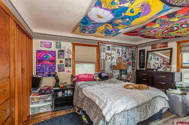 a bedroom with a bed a dresser and painting on the wall