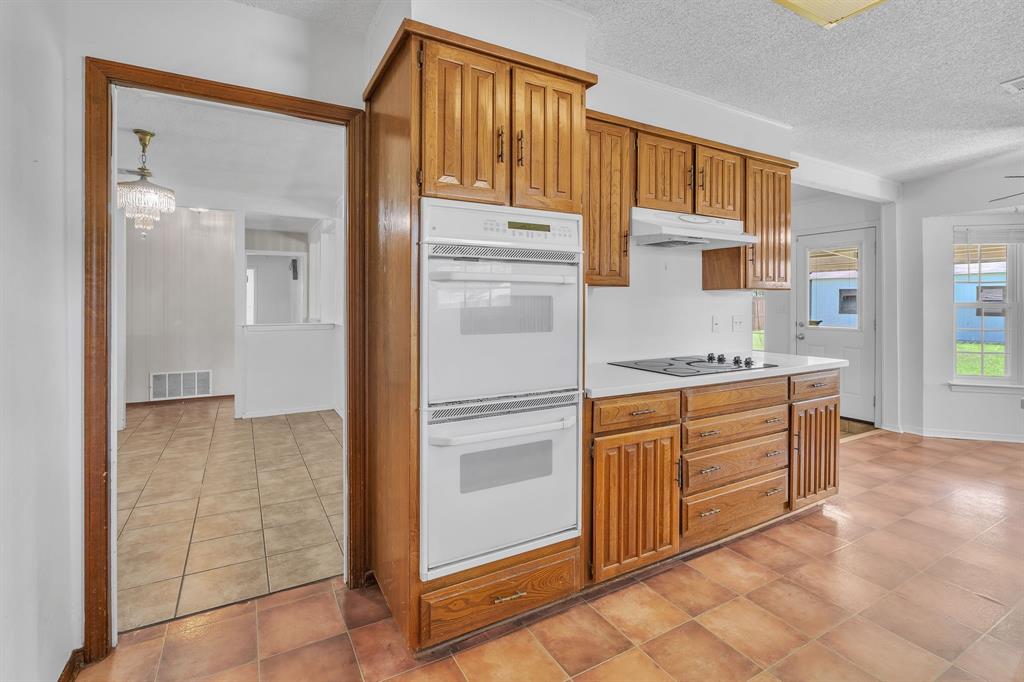 1720 Timbercreek Road Benbrook, TX 76126 - Photo 11 of 33 Kitchen featuring wood cabinetry, white countertops, built-in double ovens, and a stovetop with an overhead range hood