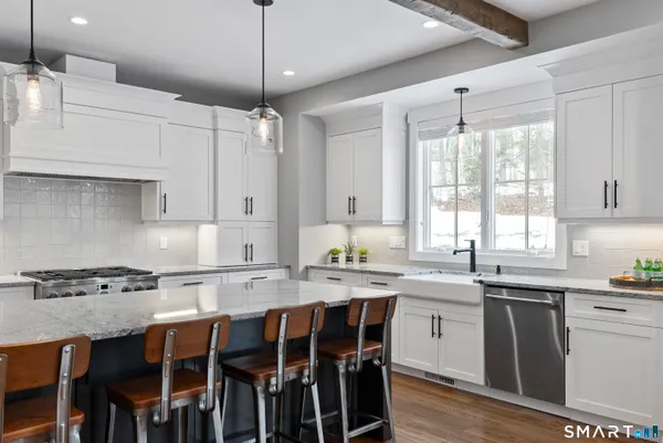 a kitchen with stainless steel appliances granite countertop a table chairs sink and cabinets