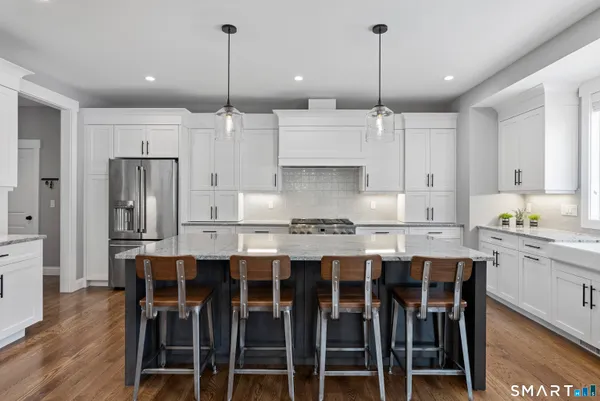 a kitchen with stainless steel appliances kitchen island granite countertop a dining table chairs sink and cabinets