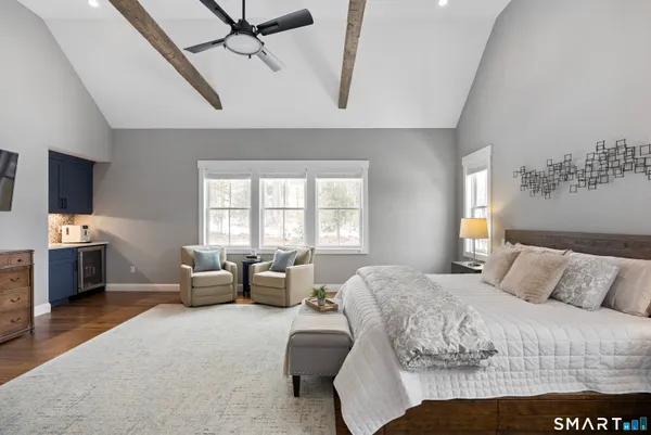 a bedroom with a bed couches and a flat tv screen