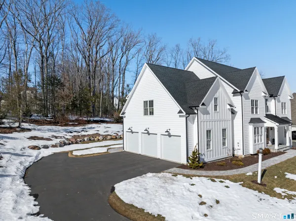 a view of a white house next to a road and yard