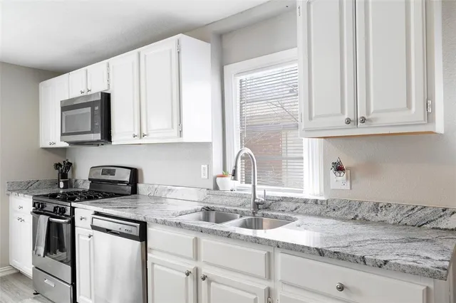 a kitchen with granite countertop white cabinets and stainless steel appliances