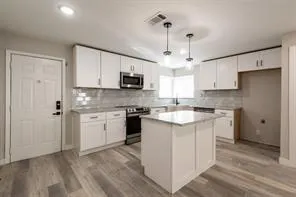 a kitchen with kitchen island granite countertop a sink window and stainless steel appliances