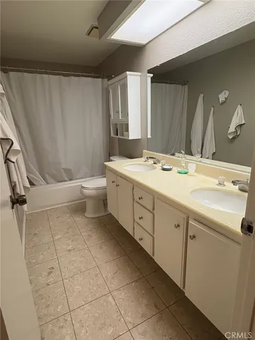 a spacious bathroom with a granite countertop sink a toilet mirror and a bathtub