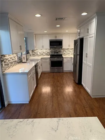 a kitchen with stainless steel appliances granite countertop a sink stove refrigerator and cabinets