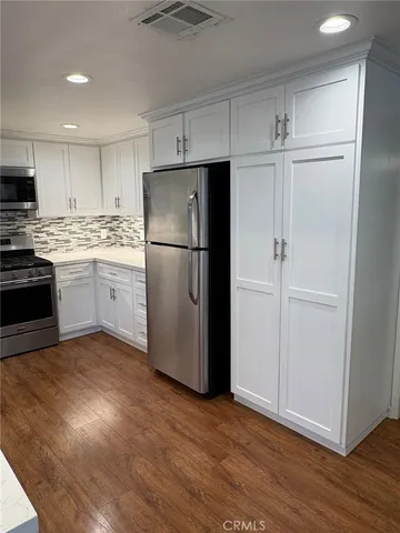 a kitchen with a refrigerator a stove top oven and wooden floor